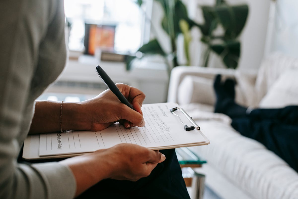 Person writing reflectively in a notebook in a calm, well-lit room